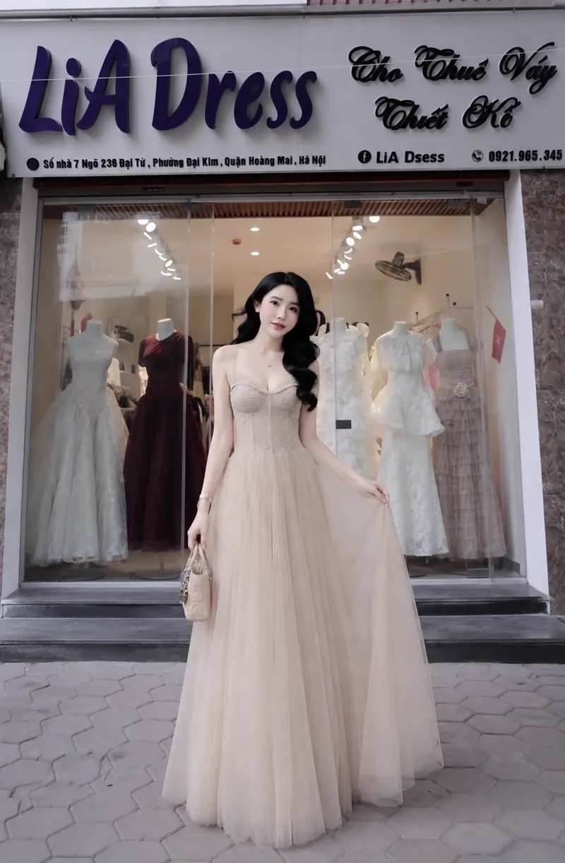 Người mẫu mặc đầm dạ hội tulle màu champagne dài chấm gót trước showroom LiA Dress tại Đại Từ, Hoàng Mai.